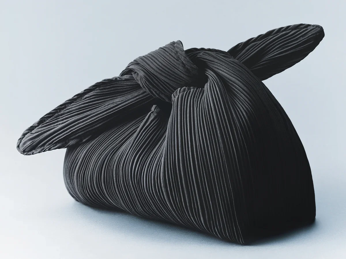 The black knotted Signature Bag against a pale blue backdrop