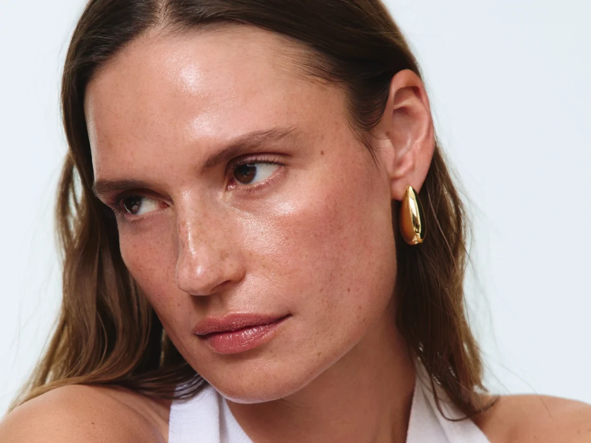 Close portrait of a woman with a gold hoop earring and fresh, bare skin