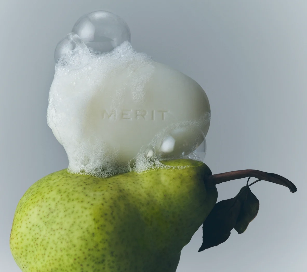 A green pear with a cloud of white cleanser foam on top