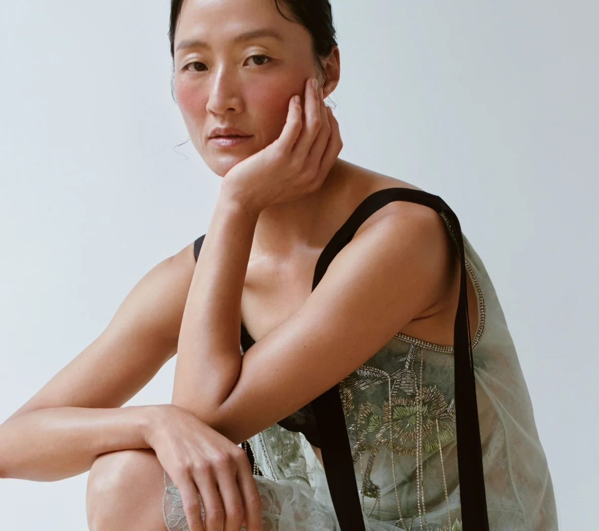 Woman in a linen top resting her chin on her hand