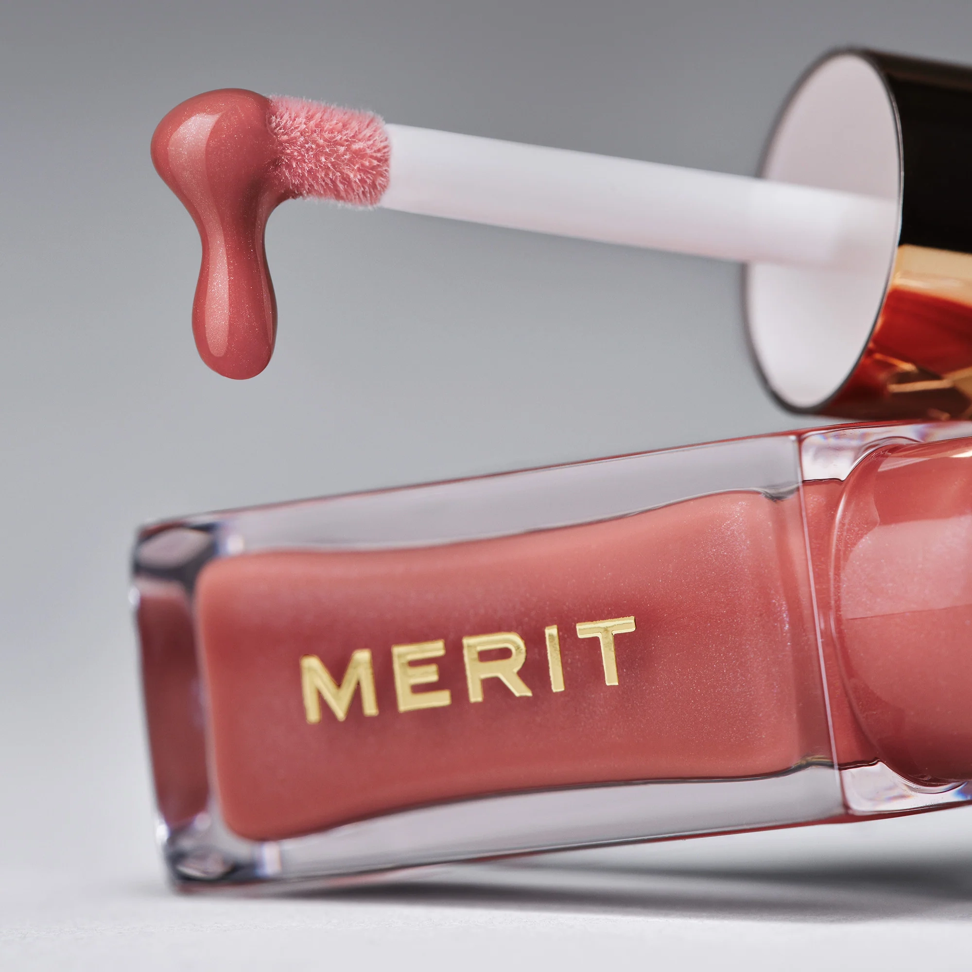 Up close, Shade Slick lip oil dripping off its applicator