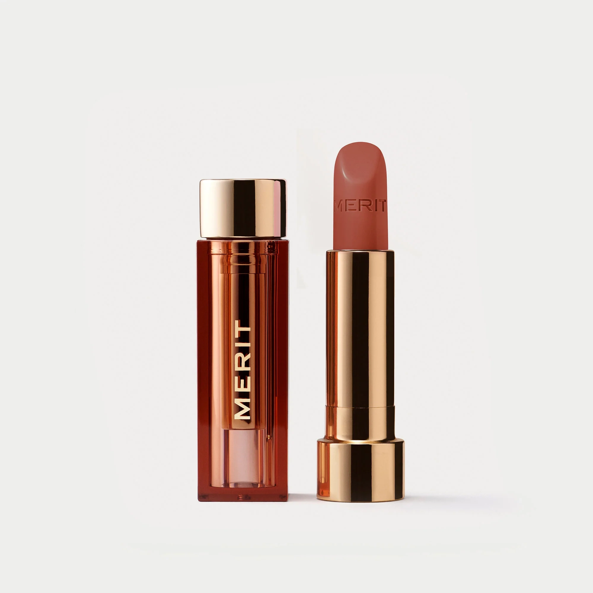 A lipstick in the shade Ginger beside its open container