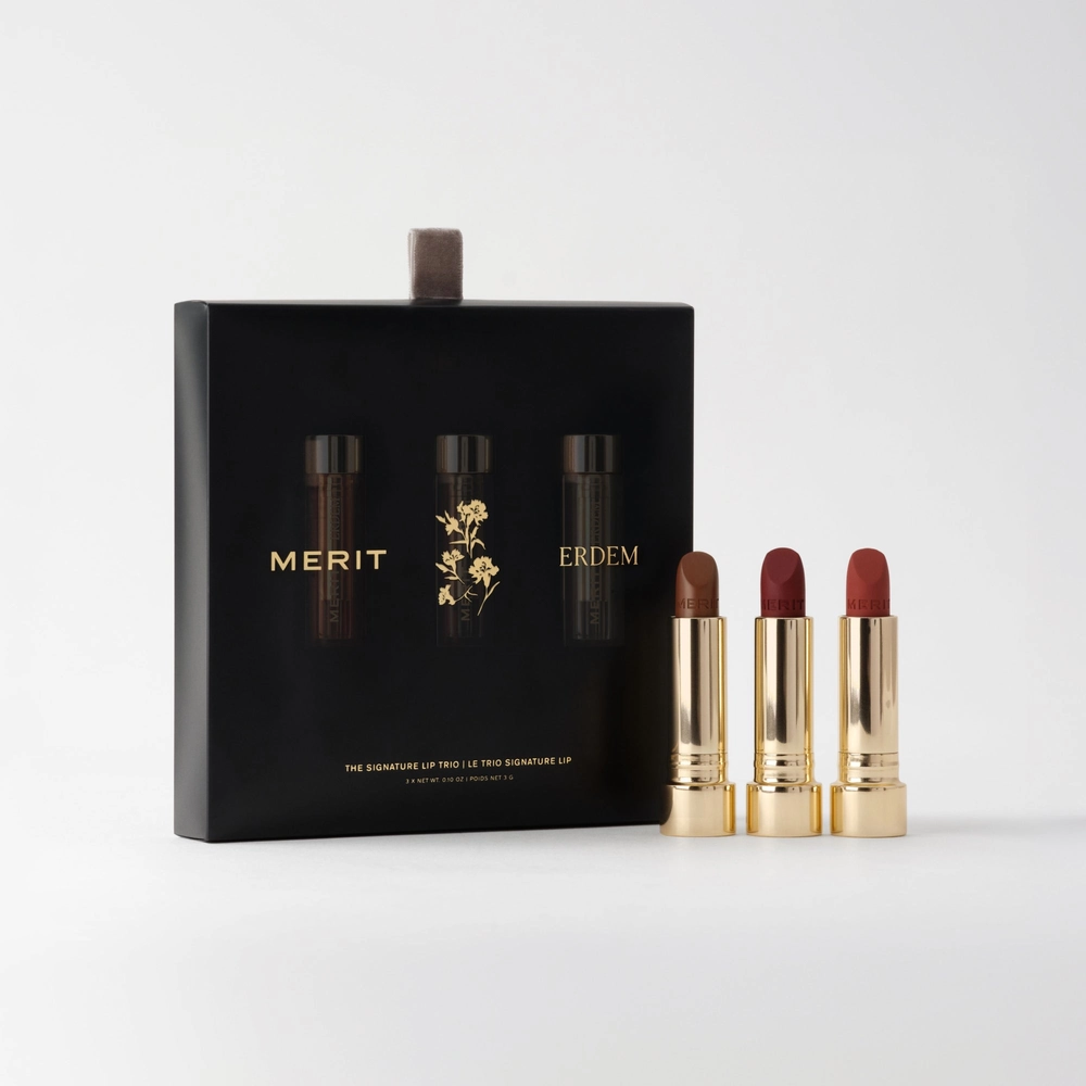 Black box of the Signature Lip Trio next to three gold lipsticks